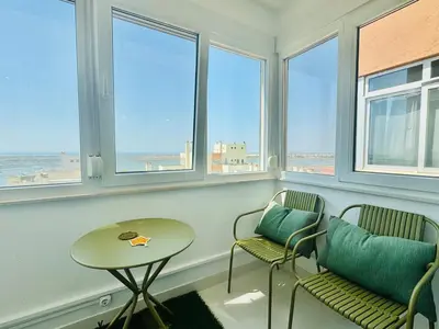 a room with two chairs and a table and windows at Doble Vista Faro, Terrace with View, AC & WiFi in Faro