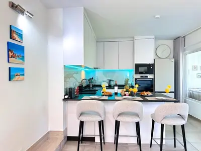 a kitchen with white cabinets and a counter with stools at Windmill Hill Gem Townhouse By BeCherish in Albufeira