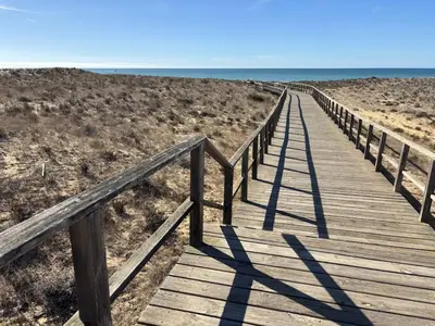 a wooden boardwalk leading down to the beach at Casa Sauchi mit Gemeinschaftspool - Neu renoviert in Albufeira