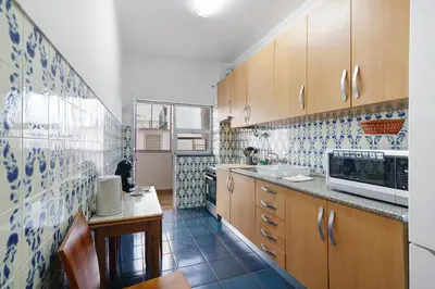a kitchen with wooden cabinets and blue and white tiles at Happy House Central Apartment in Faro
