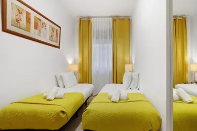 a hotel room with two beds with yellow sheets at Happy House Central Apartment in Faro
