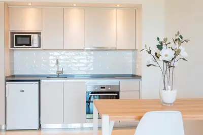 a kitchen with white cabinets and a table with a vase of flowers at Alfagar Prestige in Albufeira