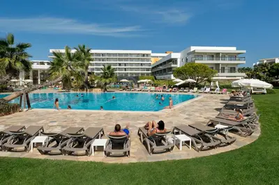 a group of people sitting in lounge chairs by a pool at Alfagar Prestige in Albufeira
