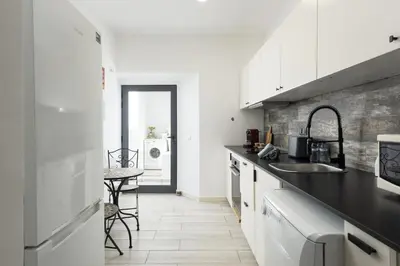 a kitchen with white cabinets and a black counter top at Marggisa - City Center by HD in Faro