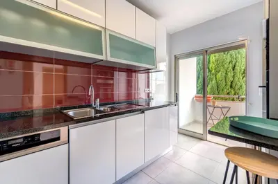 a kitchen with white cabinets and a large window at Apartamento Vista Piscina in Guia