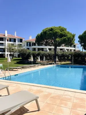 a large swimming pool with chairs and a building at Luxury Apartment in Vila Sol Resort in Quarteira