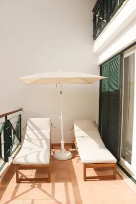 two chairs and a white umbrella on a porch at Luxury Apartment in Vila Sol Resort in Quarteira