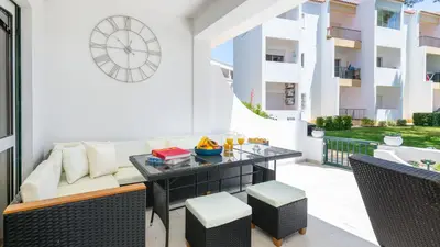 a patio with a couch and a table and a clock at Lounge Garden Apartment in Vilamoura