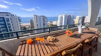 a wooden table with glasses of orange juice and bread on a balcony at Ocean View Quarteira in Quarteira