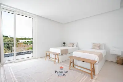 a white bedroom with two beds and a large window at Modern 4-Bedroom Villa with Infinity Pool in Albufeira