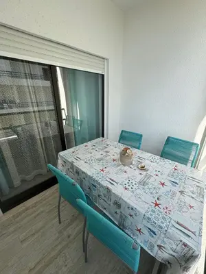 a dining room table with two blue chairs and a table with a table cloth at Beach House in Quarteira