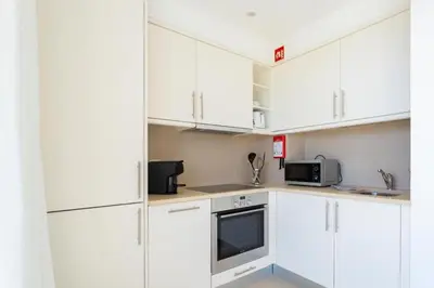 a white kitchen with white cabinets and a microwave at Snazzy Varandas do Castelo One Bedroom Apartment with Sea View sleeps 2 in Albufeira