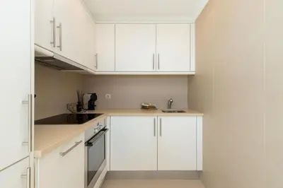a white kitchen with white cabinets and a sink at Snazzy Varandas do Castelo By Garvetur One Bedroom Apartment sleeps 2 persons in Albufeira