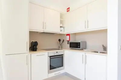 a white kitchen with white cabinets and a microwave at Snazzy Varandas do Castelo By Garvetur One Bedroom Apartment sleeps 2 persons in Albufeira