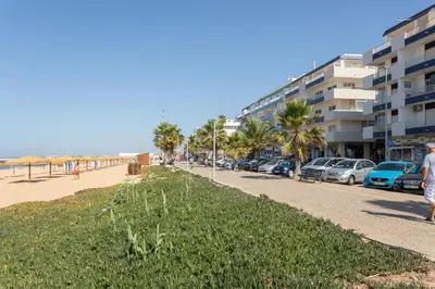 a street next to a beach with palm trees and buildings at AL - Apartamentos Vista Mar in Quarteira