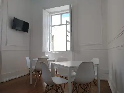 a white dining room with a white table and chairs at Baixa Terrace Hostel in Faro