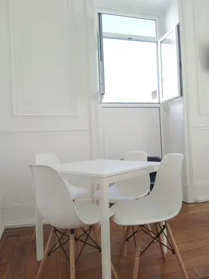 a white table and chairs in a room with a window at Baixa Terrace Hostel in Faro