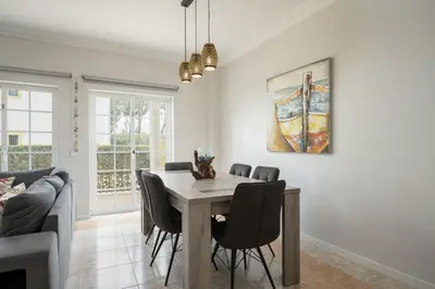 a dining room with a table and chairs and a couch at Mar e Golfe - Pool with golf view by HD in Vilamoura