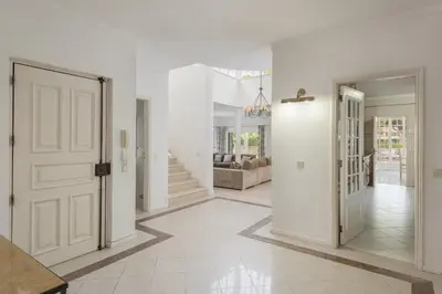 a white hallway with a door and a living room at Vila Popa - Golf Front with Games Room by HD in Vilamoura