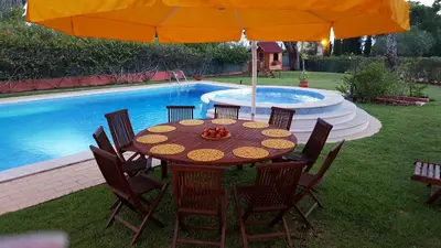 a table and chairs under an umbrella next to a pool at Vila Luz in Vilamoura