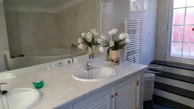 a bathroom with two sinks and a tub with flowers at Vila Luz in Vilamoura