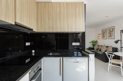 a kitchen with black and white appliances and a living room at Marina Praia - Marina view by HD in Vilamoura