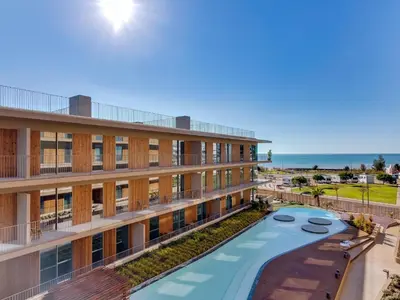 an apartment building with a pool and the ocean in the background at 2bdr Horizon Sand apartment in Quarteira in Quarteira