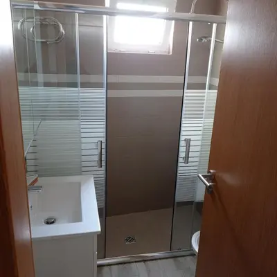 a glass shower in a bathroom with a sink at Casa do Outeiro - T2 Quarteira velha in Quarteira