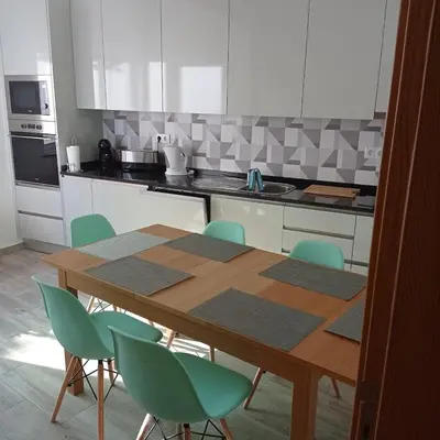 a kitchen with a wooden table and green chairs at Casa do Outeiro - T2 Quarteira velha in Quarteira