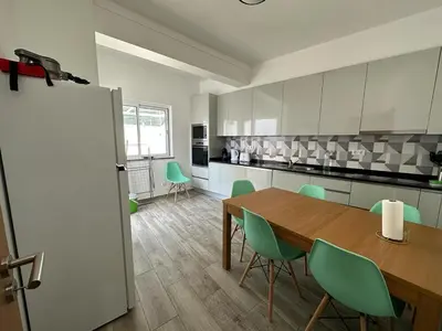 a kitchen with a wooden table and green chairs at Casa do Outeiro - T2 Quarteira velha in Quarteira