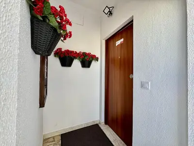 a hallway with red flowers in baskets on the wall at Albufeira Shine by Homing in Albufeira