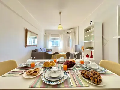 a table with plates of food on it in a living room at Quarteira Central 3 by Homing in Quarteira