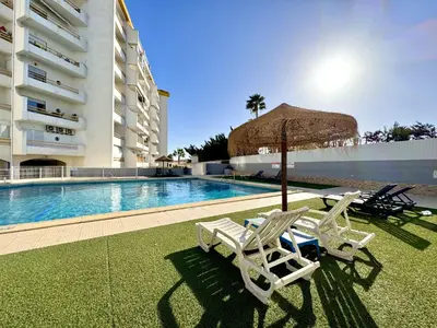 two lounge chairs and an umbrella next to a swimming pool at Albufeira Vintage Apartment 2 With Pool by Homing in Albufeira