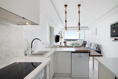 a white kitchen with a sink and a counter at Delmar in Quarteira