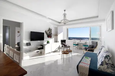 a white living room with a tv and a couch at Delmar in Quarteira