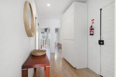 a hallway with white walls and a table and a mirror at Abertura Mar Zen in Quarteira