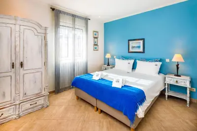 a blue bedroom with a large bed with blue walls at Pine Cliff Apartment by The Portuguese Butler in Olhos de Água