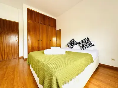 a bedroom with a bed with a green and white blanket at Faro Family Apartment in Faro
