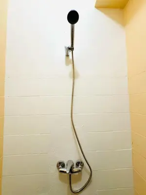 a shower with a hose attached to a wall at Faro Family Apartment in Faro