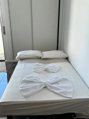 two beds with white sheets and a bow tie on them at Studio com vista para Rua da Oura - Albufeira in Albufeira