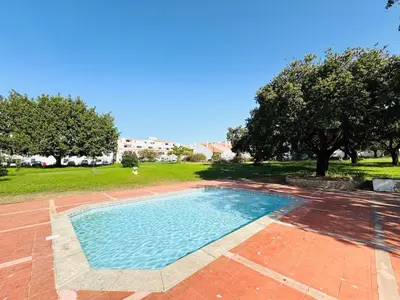 a swimming pool in a yard with trees and grass at Apartamento aconchego T1 Rua da Oura in Albufeira