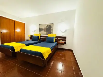 a bedroom with two beds with yellow and blue pillows at Apartamento albufeira T1 condominio vila nova in Albufeira