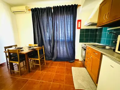 a kitchen with a table and a blue curtain at Apartamento albufeira T1 condominio vila nova in Albufeira