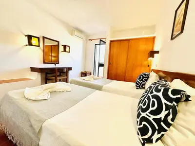 a hotel room with two beds and a desk at Condominio privado T1 Rua da Oura in Albufeira