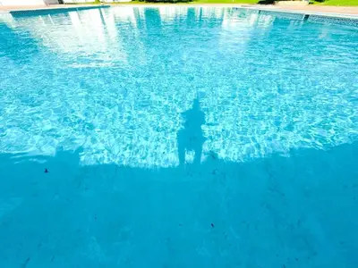 a man standing in a pool of blue water at Condominio vila nova T1 Rua da Oura in Albufeira