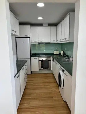 a kitchen with white cabinets and green walls at Sundown Pines Vilamoura in Quarteira