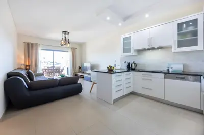 a kitchen with white cabinets and a couch in a room at Almargem Apartment in Quarteira