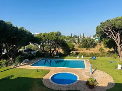 a swimming pool in a yard with a grassy field at The Sun of Quarteira in Quarteira