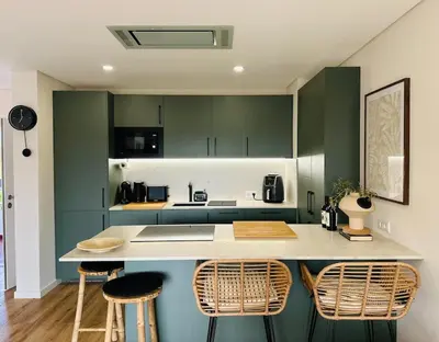 a kitchen with green cabinets and a counter with stools at The Sun of Quarteira in Quarteira