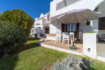 a white house with a patio with an umbrella at My Inzu by HelloVacations in Albufeira